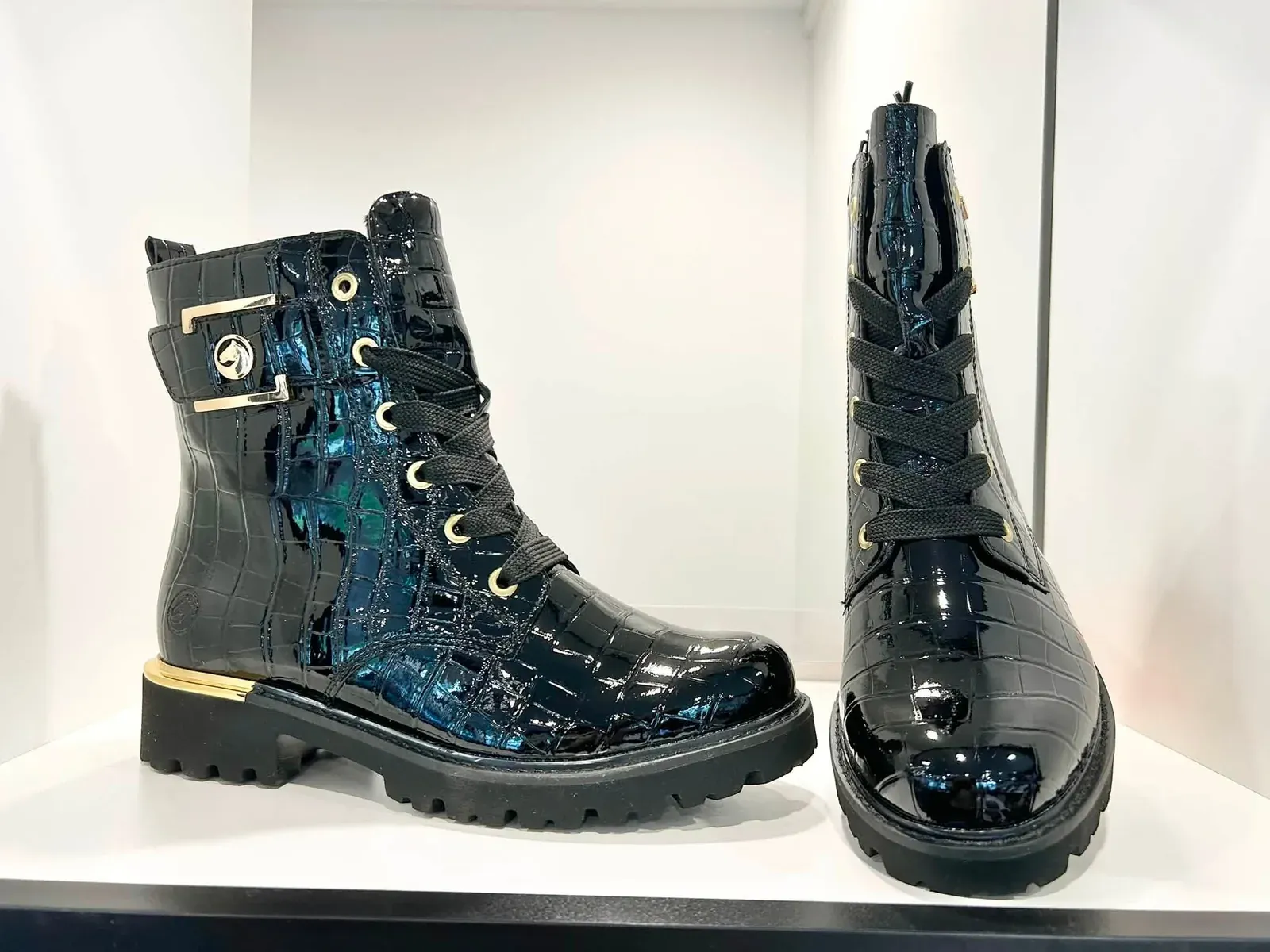 Deux bottines noires vernies à semelle crantée, présentées en magasin